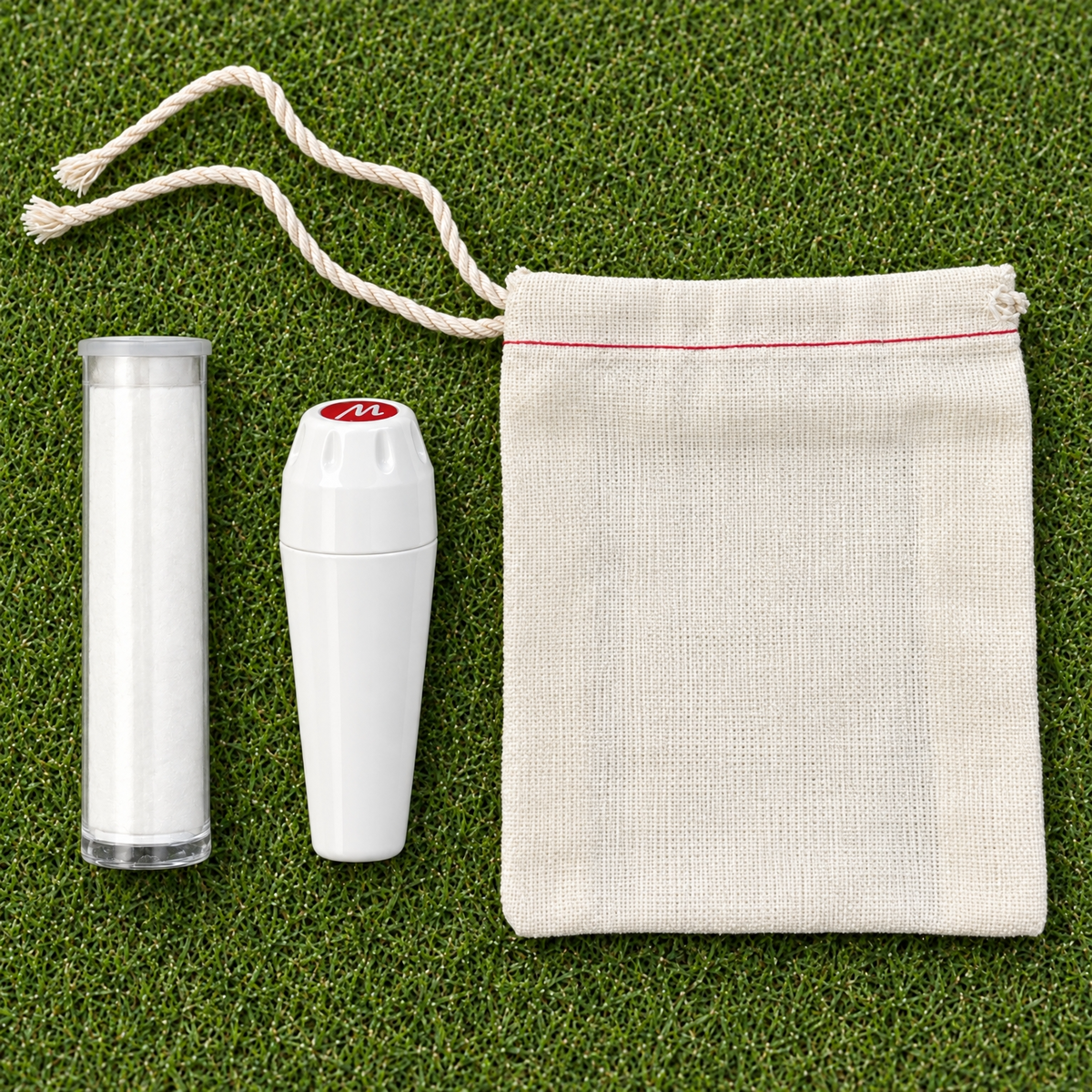 White Marc-it marker, white powder refill tube, and cotton drawstring pouch on a putting green.